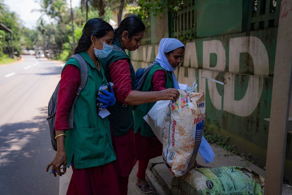 Green worms workers inspect sacks of waste material