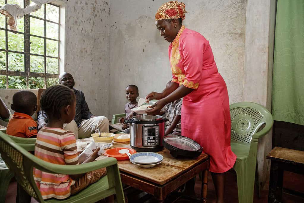 Woman serve her family dinner at the table from a BURN electric pressure cooker