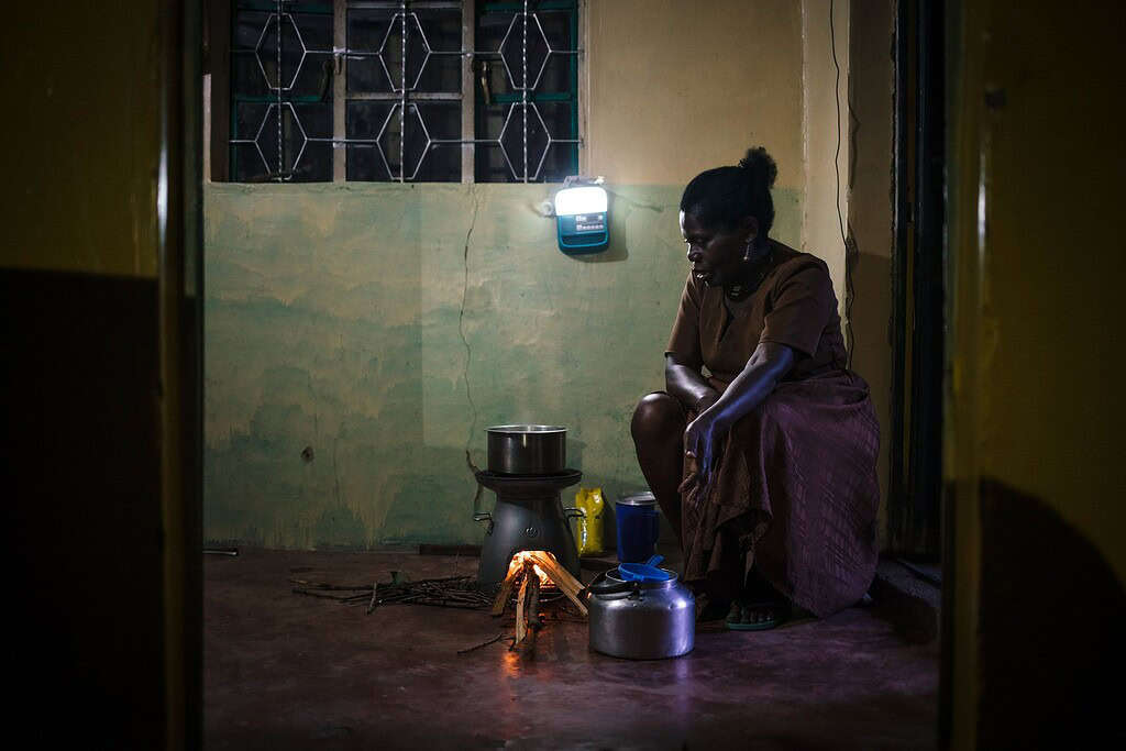 Woman prepares food while using solar powered lamp
