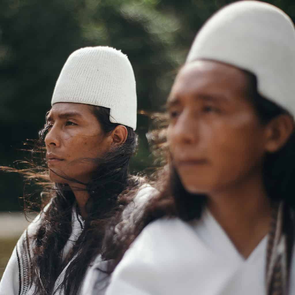 Two indegenous farmers relax in the breeze while riding a small boat through a rural Colombia river