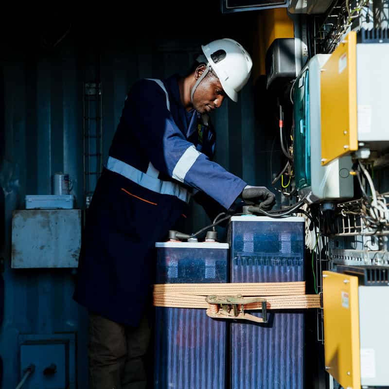 Technician works on solar power array in East African shed