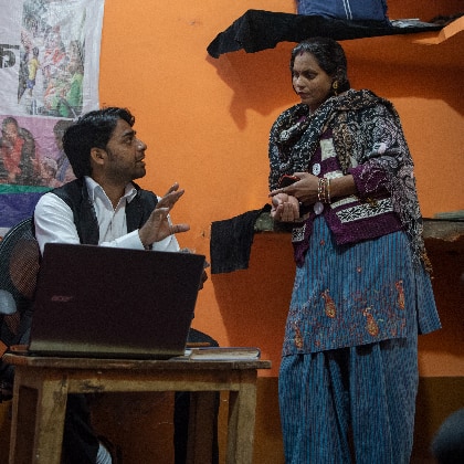 Man speaks to woman while sitting at a table with a laptop in India