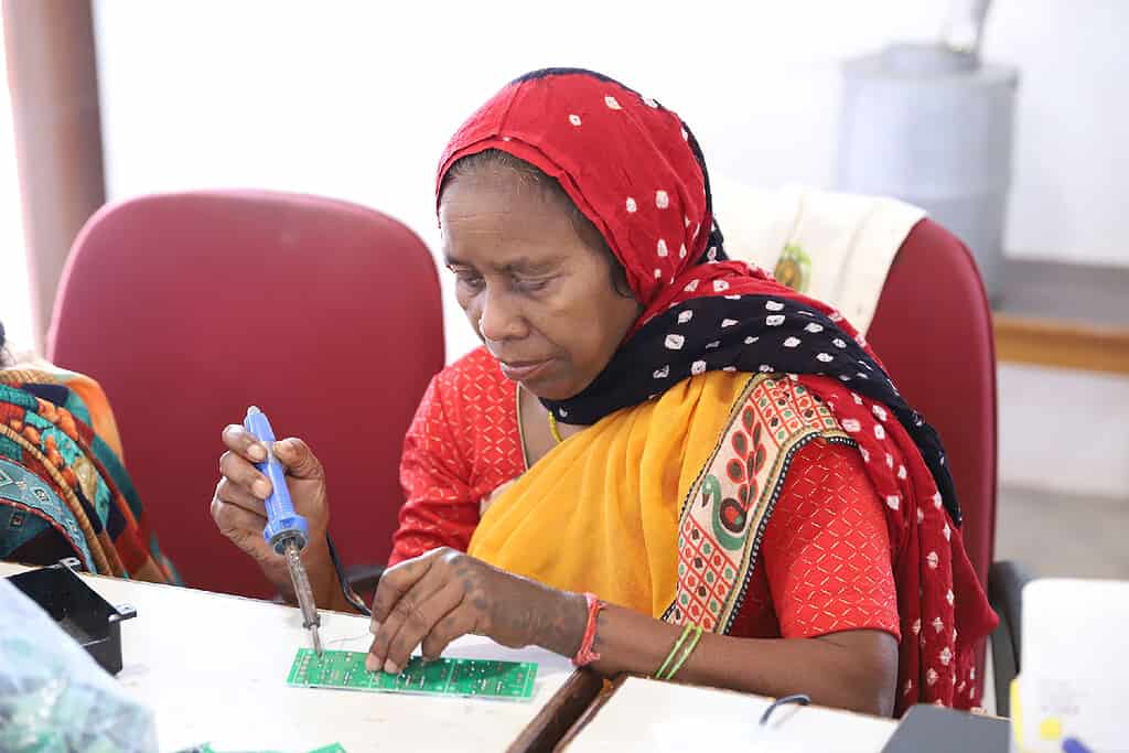 Woman solders electrical board in India