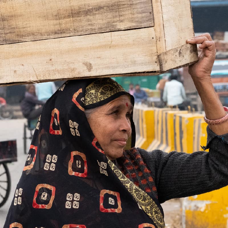 Women carries wooden box on her head across busy Indian road