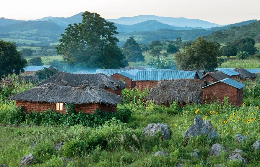Scenic landscape of rural community with brick houses. Some houses have straw roofs while others have metal roofs
