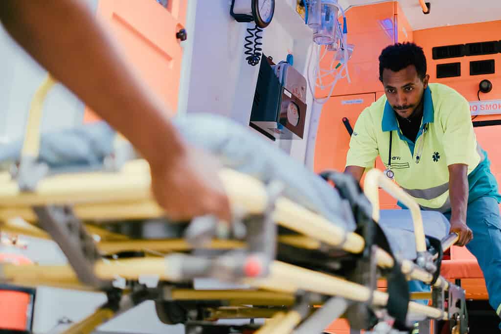 Ambulette worker securing stretcher within to Ambulette
