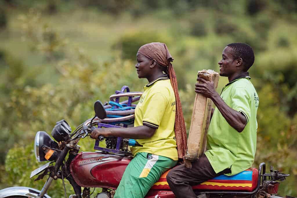 Man and women ride a motorcycle in East Africa while carrying solar panel equipment