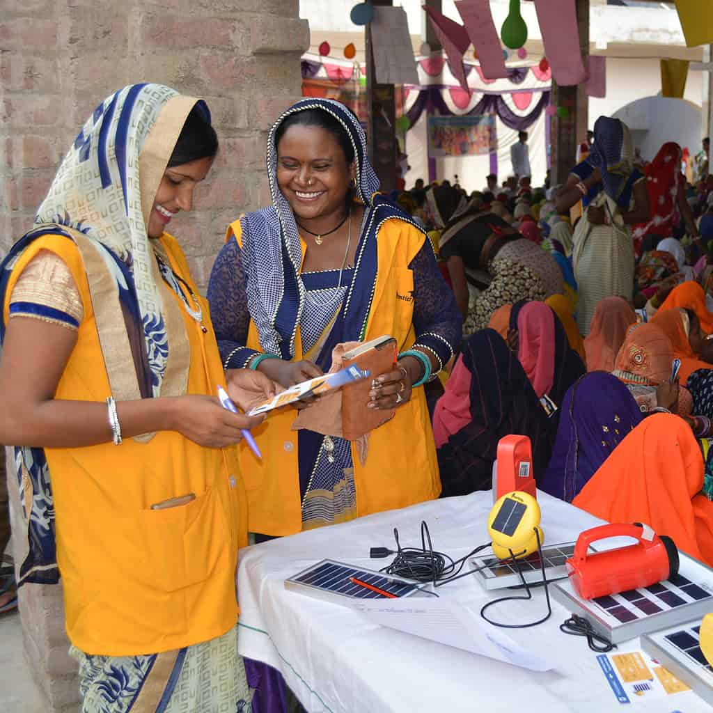 People in colorful attire, acquiring solar equipment, suggestive of investing in entrepreneurs.