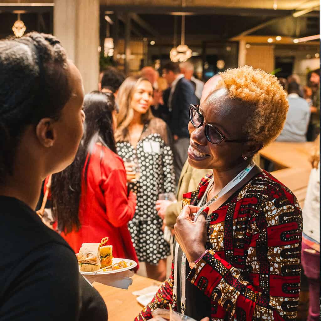 An image of two people smiling, appearing to be in conversation at an international event.