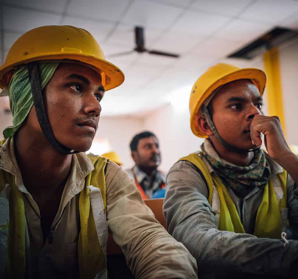 Two workers listen intently to lecture on construction practices in India.