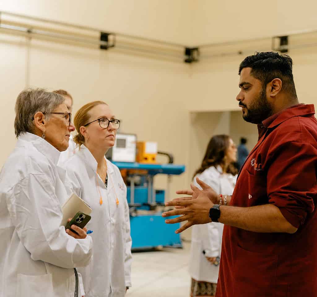 Two investors tour facility and listen intently to worker