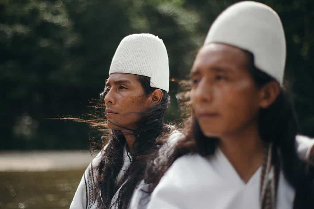 Two indegenous farmers relax in the breeze while riding a small boat through a rural Colombia river