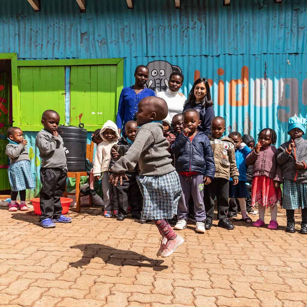 Child jumps surrounded by fellow classmates and teachers in a school yard