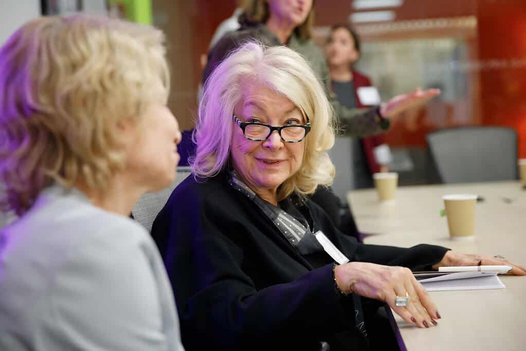 Acumen Partner and Board Emeritus, Margo Alexander chatting at a table