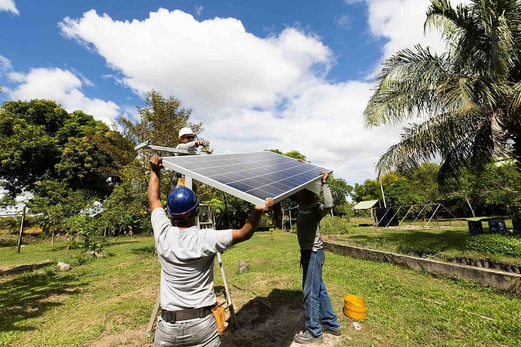 Workers securely move a solar panel during installation