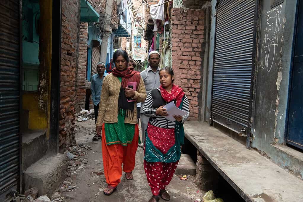 Women walk through a busy city alleyway in India. Photo of Acumen investee Haqdarshak